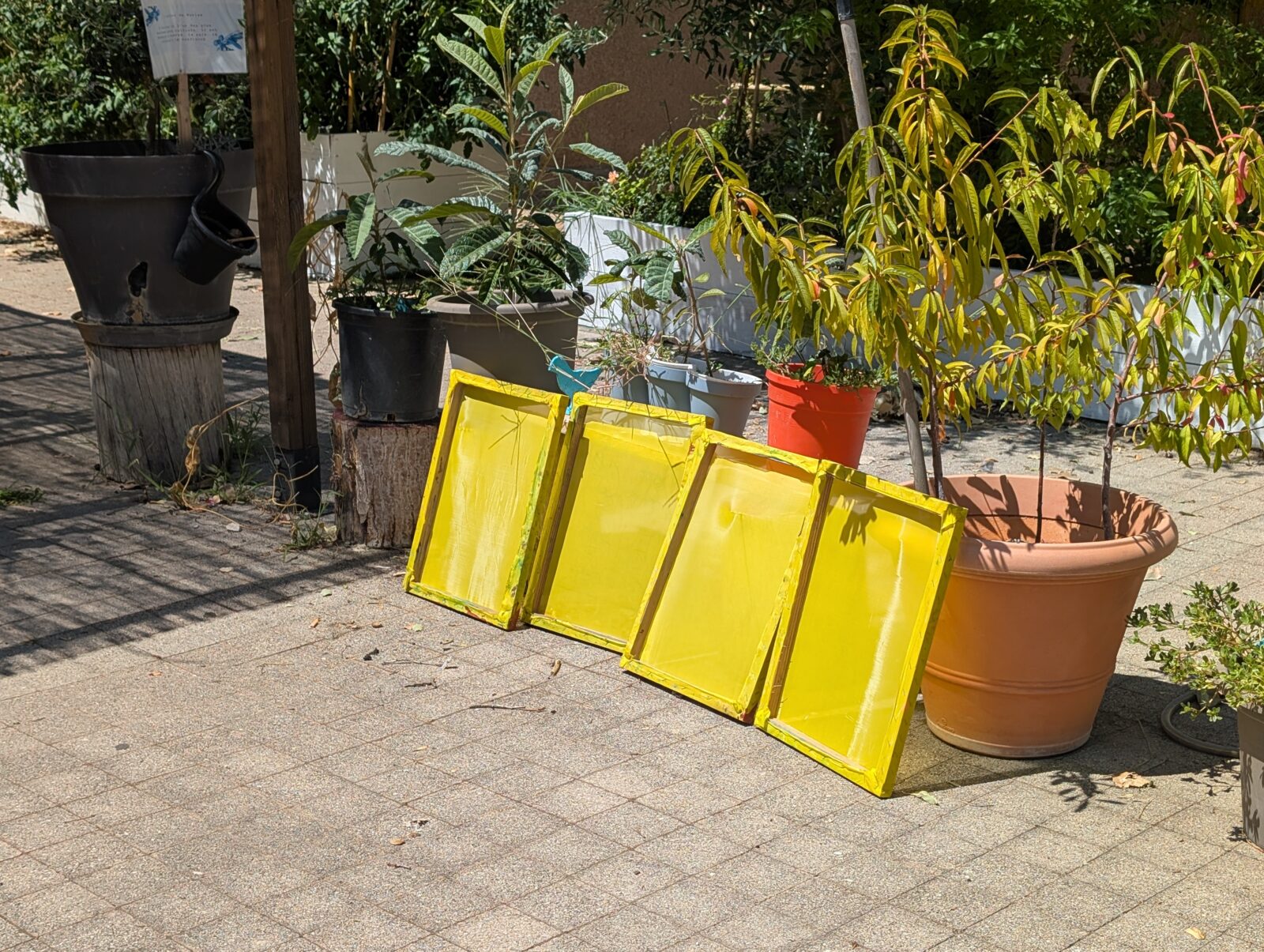 Les cadres de sérigraphie sèchent au soleil, après un coup de main des résidents pour faire fonctionner le Kärscher.